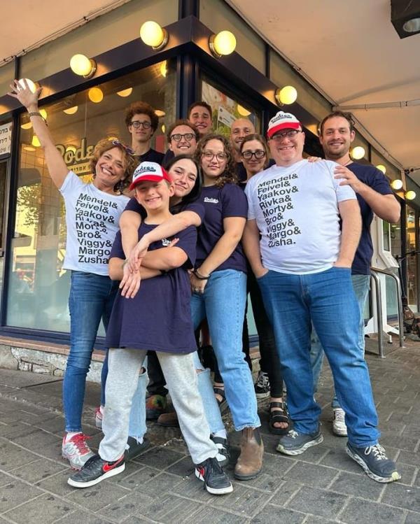 James Oppenheim (right, in white shirt) and his wife (left, in white shirt) with their nine kids outside their Tel Aviv restaurant.