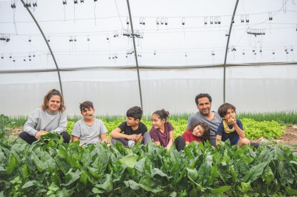 Michal Havivian, her husband, and five kids kneeling on the groun with plants